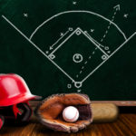 Baseball equipment consisting of glove, helmet, bat and baseball with background play strategy drawn on chalk board.